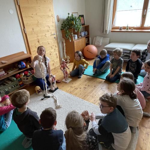 Kinder im Sitzkreis um das Skelett 