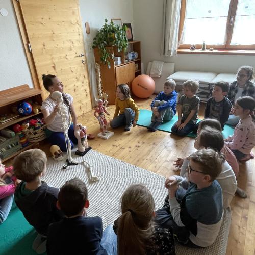 Kinder im Sitzkreis um das Skelett