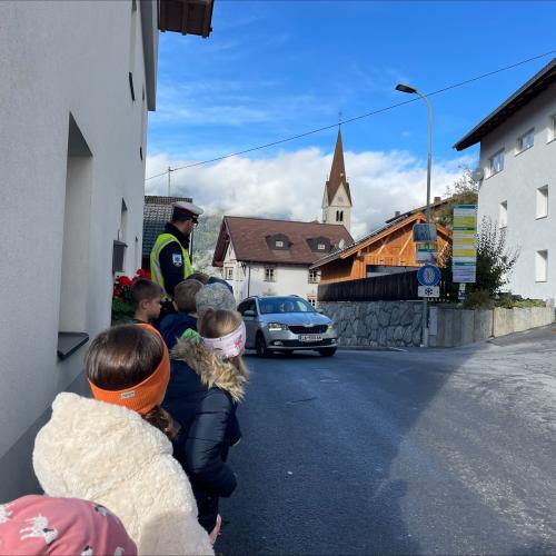 Polizist mit Kindern am Gehsteig