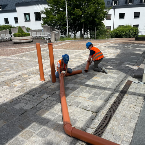 Kinder beim Rohre verlegen 